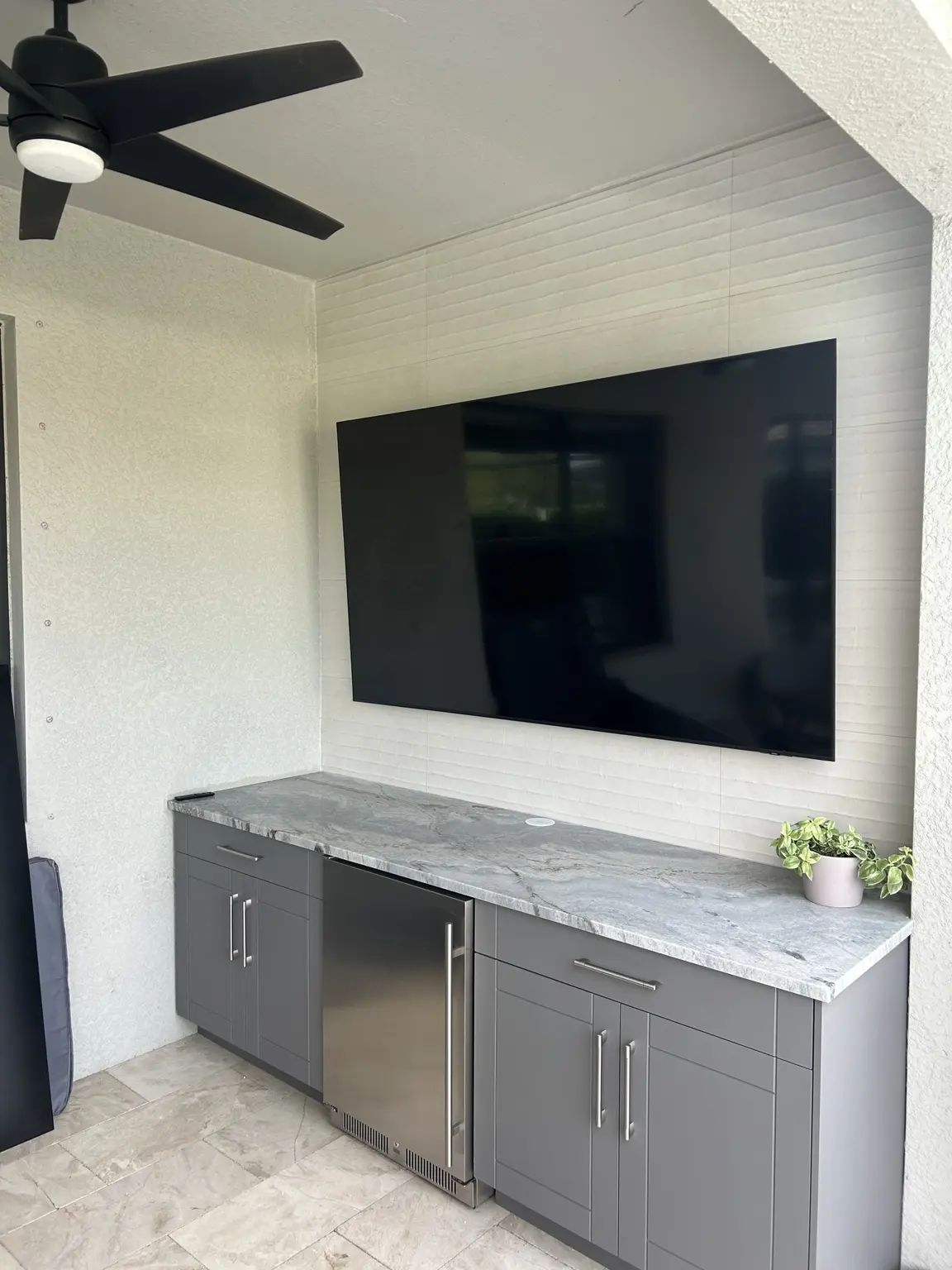 Outdoor entertainment wall with television, countertop, storage cabinets and beverage refrigerator